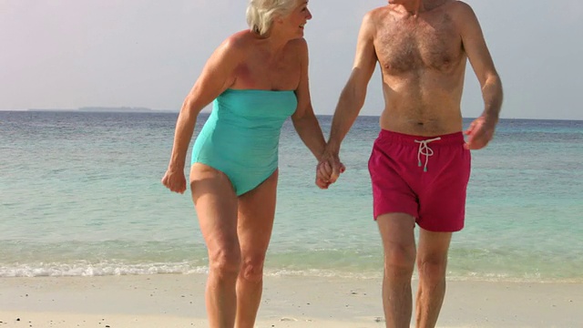一对老年夫妇在美丽的海滩上散步视频素材