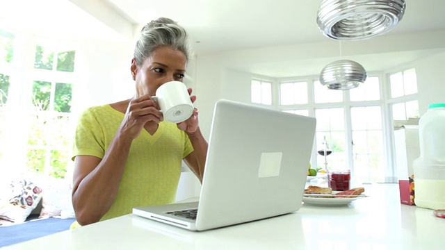 非裔美国妇女在家厨房使用笔记本电脑视频素材
