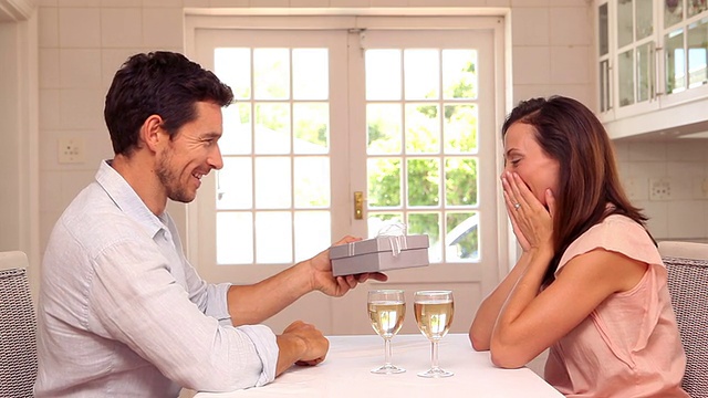 快乐的男人在餐桌上给他的伴侣一份礼物视频素材