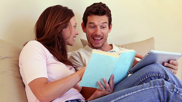 幸福的夫妇坐在沙发上一起用平板电脑视频素材