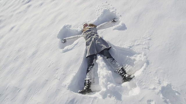 慢镜头:微笑的年轻女子堆雪天使视频素材