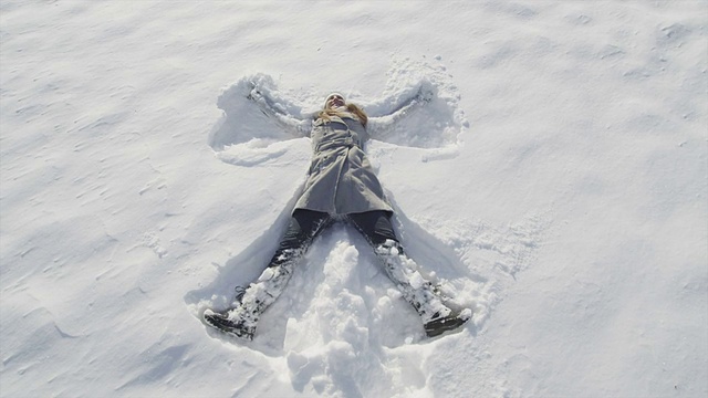 慢镜头:快乐的女人在新雪中做天使视频素材