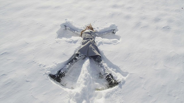 慢镜头特写:快乐的年轻女子在堆雪天使视频素材