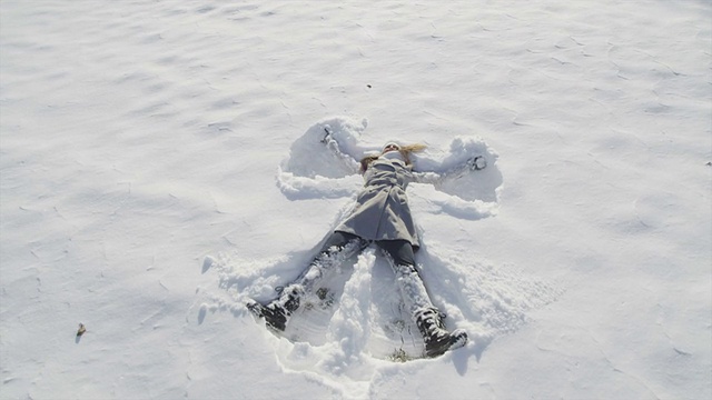慢镜头特写:年轻女子在堆雪天使视频素材