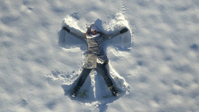 一名年轻女子在冬天制作雪天使视频下载