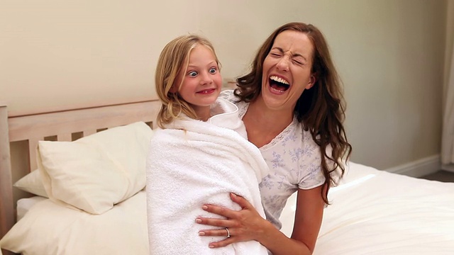 妈妈和裹着毛巾的小女孩坐在一起视频素材