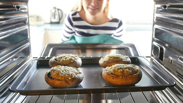 一名女子将蘑菇塞进烤箱烹饪视频素材