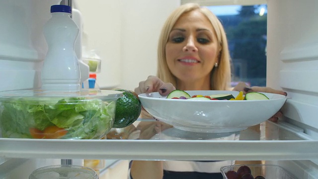 从冰箱里拿出一盘蔬菜的女人视频素材