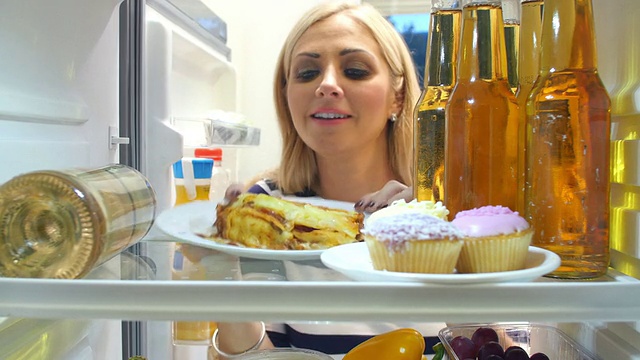 一个女人从冰箱里拿出一盘吃剩的千层面视频素材