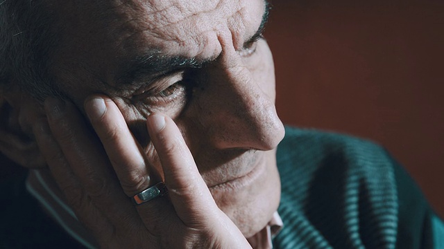 一个老人独自坐着的特写，痛苦和沮丧:悲伤的老人视频素材