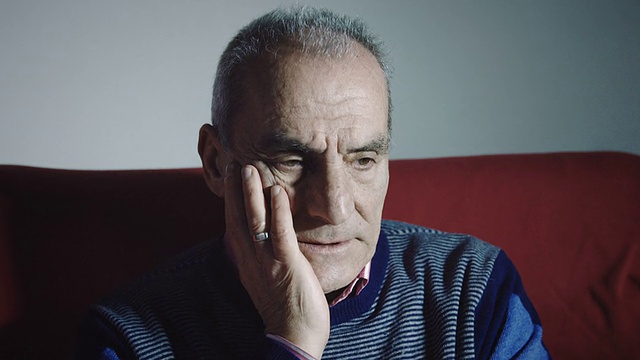 沮丧的老人独自坐在红色沙发上:沮丧，绝望，悲伤视频素材