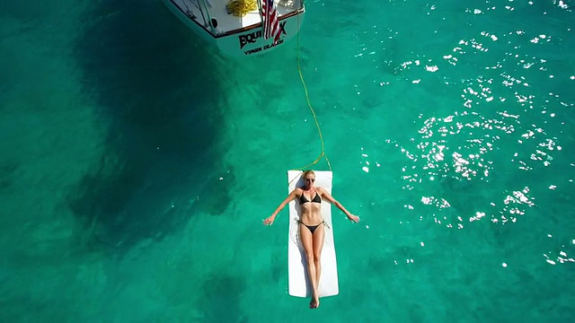 航拍视频性感女人日光浴旁边的帆船视频素材