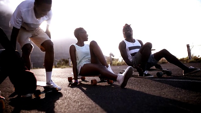 一个非洲裔美国女孩和朋友坐在长板上大笑视频素材