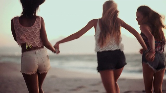 女孩们在日落海滩上牵着手奔跑视频素材