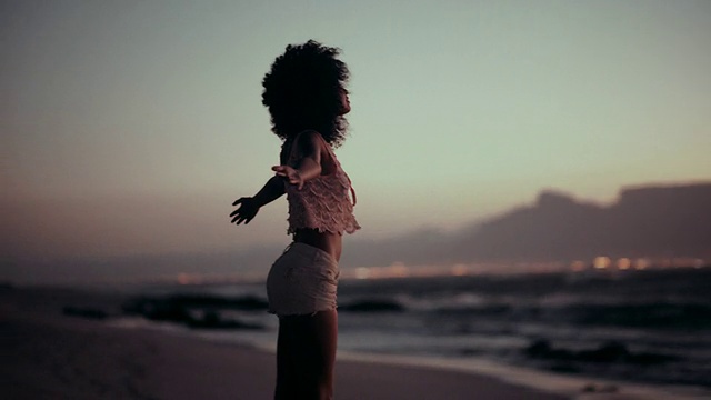 十几岁的非洲裔女孩在海滩上欣赏日落视频素材