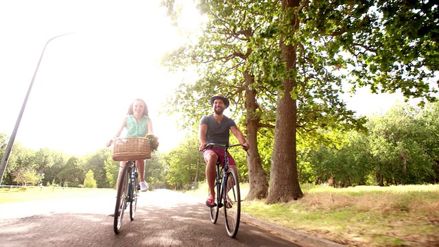 一对年轻夫妇在慢镜头中愉快地一起骑自行车视频素材