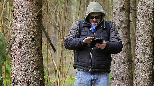 带着砍刀的徒步者，背包里有一个平板电脑在森林里视频素材