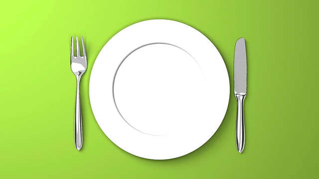 在绿色背景上的餐具和盘子俯视图视频下载