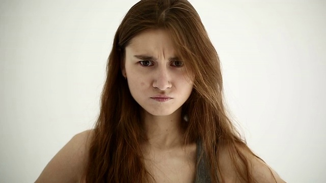 年轻女孩对着白色的背景做出愤怒的表情视频素材