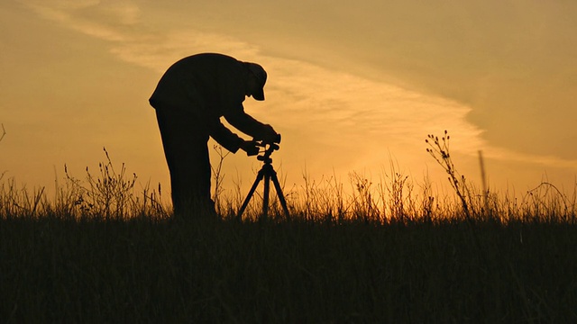夕阳下摄影师的剪影。视频下载
