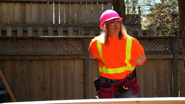 戴着粉色安全帽的女人带上了工具腰带视频下载