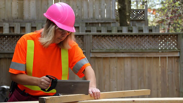 戴粉色安全帽的女人用手锯视频下载