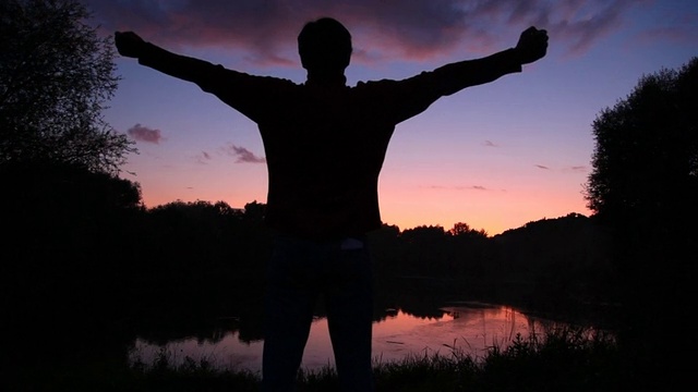 男人看着日落湖，举起手视频下载