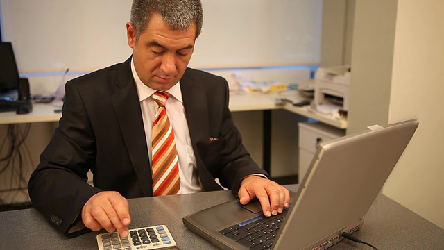 商人在办公室用笔记本电脑工作，计算视频下载