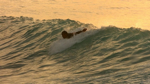 在傍晚的光线中，冲浪者划着桨进入波浪中，动作缓慢视频素材