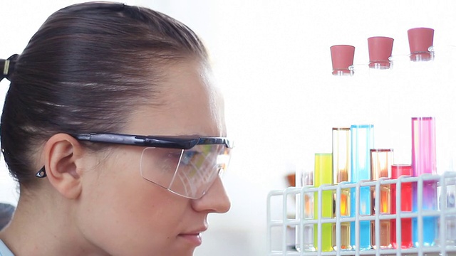 女科学家在实验室里看着五颜六色的试管视频素材