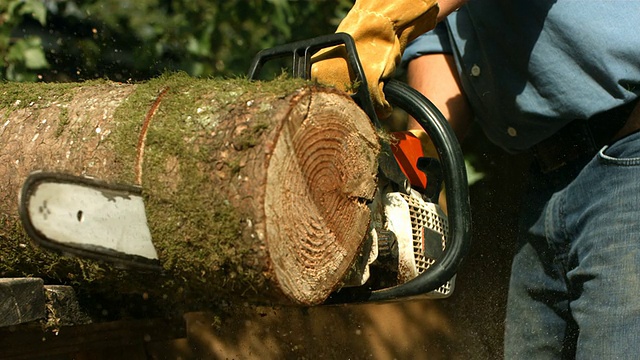 一个人用链锯切木头，慢镜头视频素材