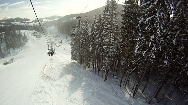 滑雪者站在滑雪缆车上。四周群山环抱，白雪皑皑。滑雪缆车上的景色视频素材