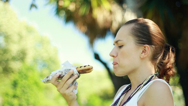 肖像快乐的女人午餐吃三明治，户外视频素材