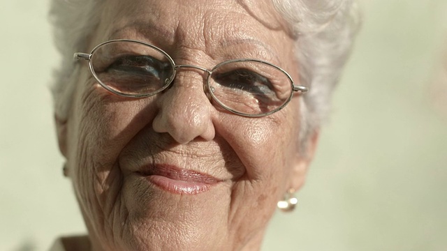 老奶奶戴着眼镜，微笑着看着镜头视频素材