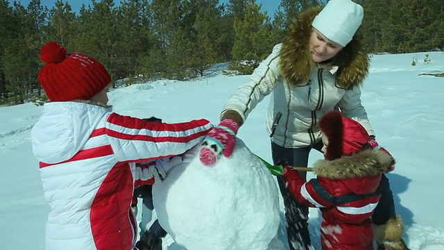 母女俩在雪地里堆雪人视频素材