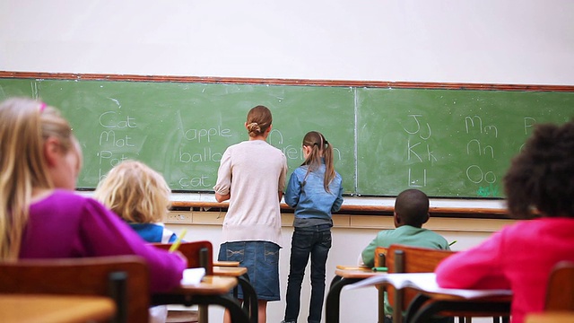 一个小学生在黑板上写字的后视图视频素材