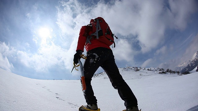 沿着积雪的山坡上山的登山者视频素材