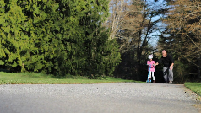 骄傲的爸爸鼓励女儿骑新踏板车视频素材