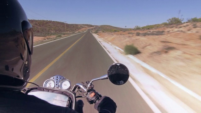 一个骑摩托车的人在一条荒凉的沙漠路上视频素材