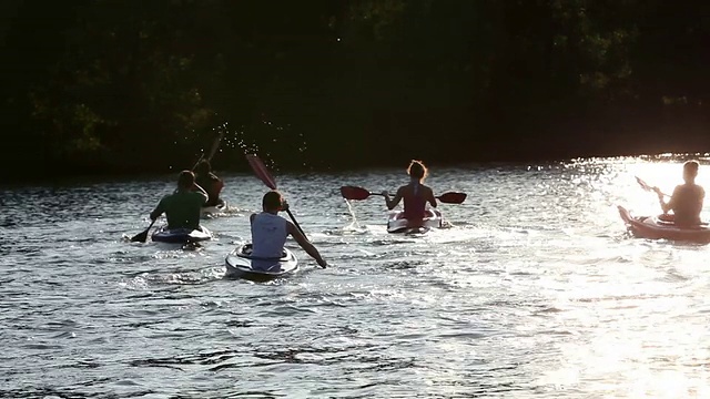 日落时分，年轻人在湖中划独木舟视频素材
