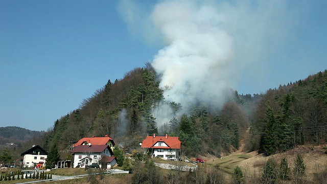 高清宽:从远处看，烟雾在森林附近的房子视频素材