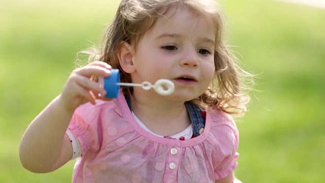 可爱的小女孩吹肥皂泡玩得很开心视频素材