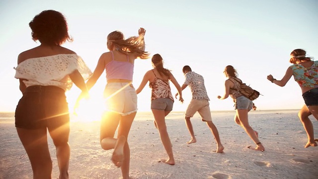 日落时分，年轻的朋友们在海滩上散步视频素材
