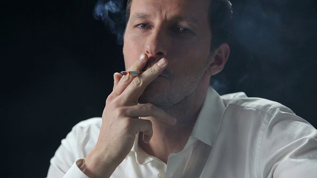 一个男人一边抽烟一边对着镜头微笑视频素材