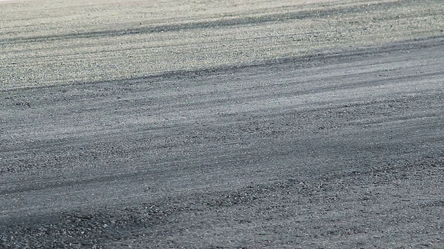 赛车在白天的比赛中经过跑道的柏油路面视频下载