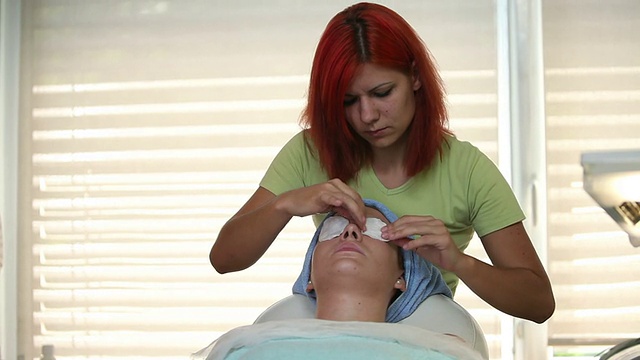 高清:女性治疗师在脸上敷面膜的中景视频下载