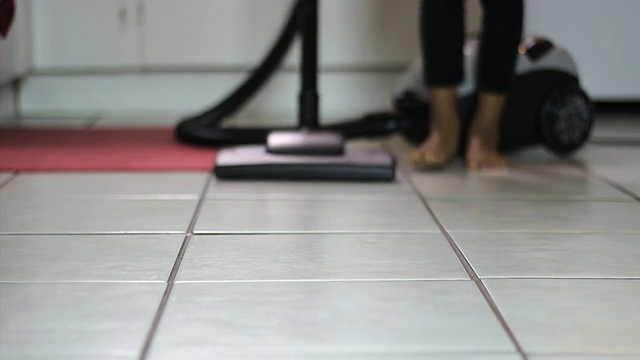 小女孩用吸尘器清洁厨房地板-低角度视频素材