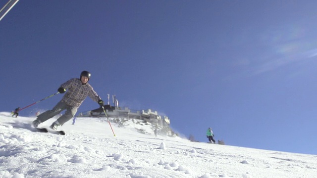 慢动作:在斜坡上滑雪的滑雪者。向相机喷雪视频素材