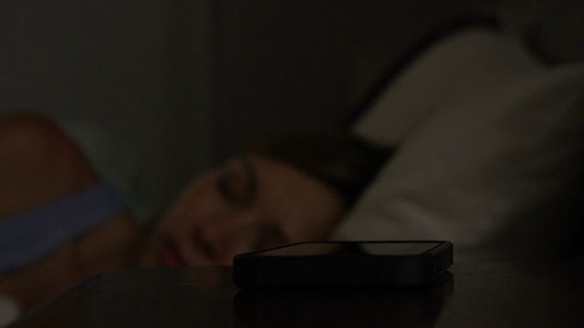 一对中年夫妇和一个被电话吵醒的女人在床上视频素材