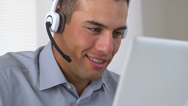 微笑的西班牙电话推销员在电脑前工作视频素材